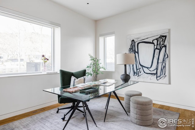home office featuring visible vents, baseboards, wood finished floors, and a healthy amount of sunlight