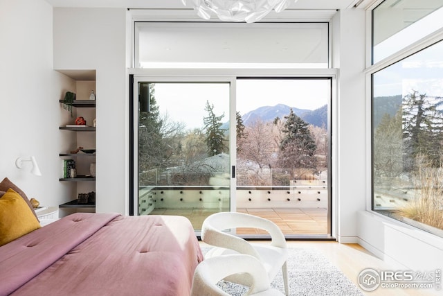 bedroom featuring access to outside, a mountain view, and wood finished floors