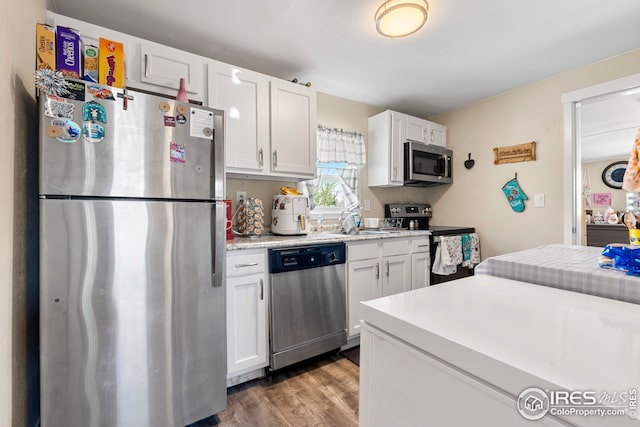 kitchen featuring white cabinets, appliances with stainless steel finishes, a sink, light countertops, and wood finished floors