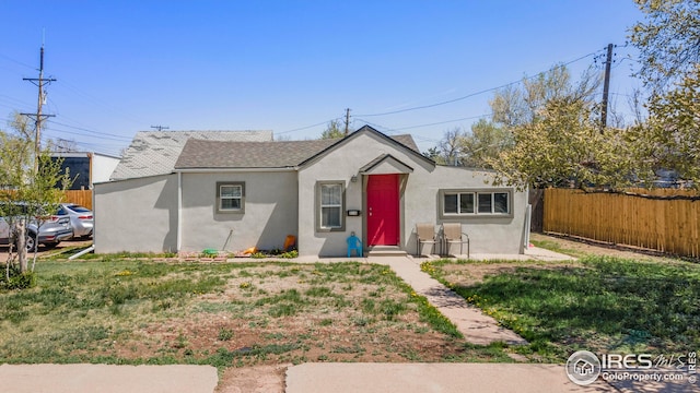 bungalow-style home featuring stucco siding, roof with shingles, and fence