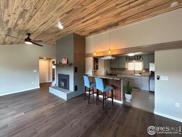 kitchen with a breakfast bar area, a ceiling fan, wooden ceiling, baseboards, and a peninsula