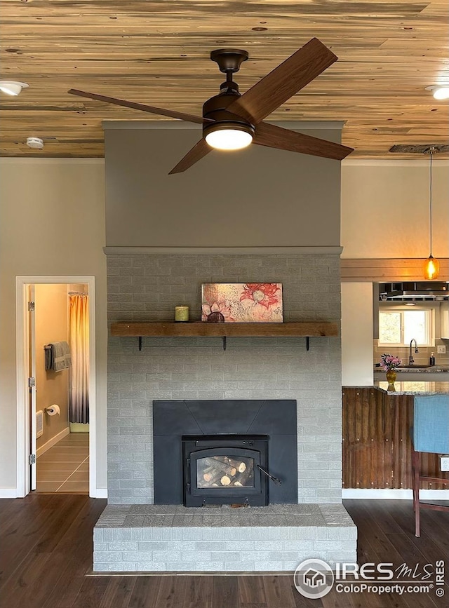 interior details with a brick fireplace, a ceiling fan, baseboards, wood finished floors, and wood ceiling
