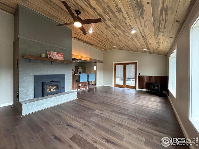 unfurnished living room with a wood stove, a fireplace, a ceiling fan, wooden ceiling, and vaulted ceiling