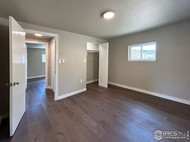 unfurnished bedroom featuring baseboards, dark wood finished floors, and a closet