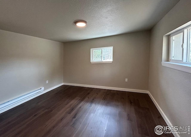unfurnished room featuring baseboards, baseboard heating, and dark wood-type flooring