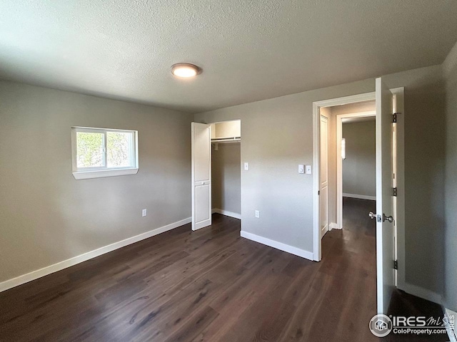 unfurnished bedroom with dark wood-style flooring, baseboards, a closet, and a textured ceiling