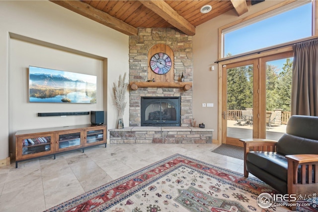 living room featuring beamed ceiling, a stone fireplace, wood ceiling, and tile patterned flooring