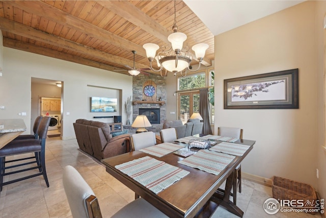 dining area with a chandelier, a stone fireplace, washer / dryer, beamed ceiling, and wood ceiling