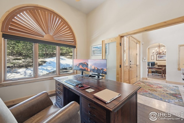 office space with tile patterned floors, baseboards, arched walkways, and a chandelier