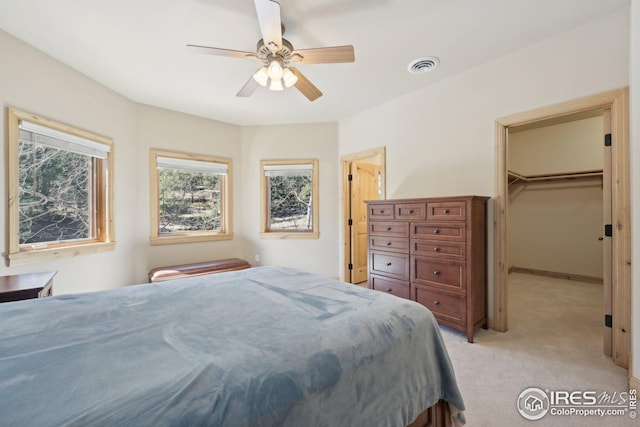 bedroom with ceiling fan, light carpet, a walk in closet, visible vents, and a closet