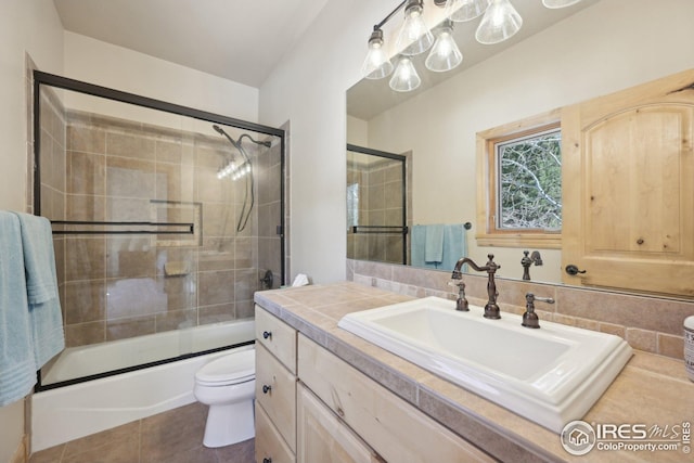 bathroom with vanity, tile patterned flooring, toilet, and shower / bath combination with glass door