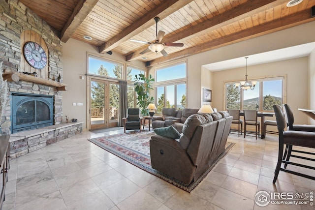 living area featuring a stone fireplace, ceiling fan with notable chandelier, wooden ceiling, and beamed ceiling