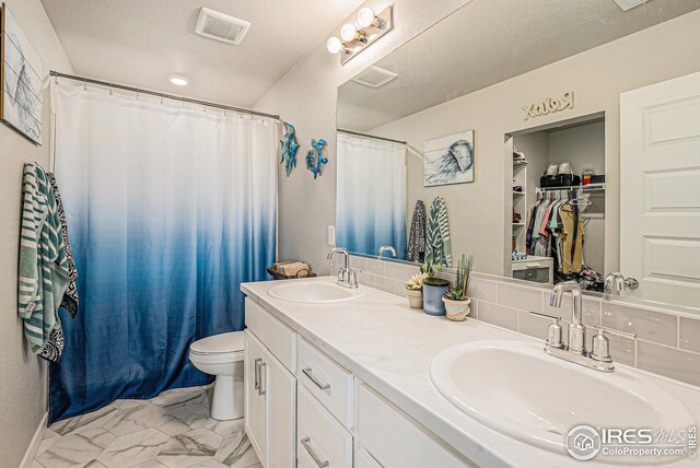full bathroom featuring double vanity, toilet, visible vents, and a sink