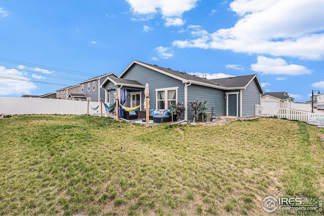 rear view of property featuring an outdoor living space, a fenced backyard, and a yard