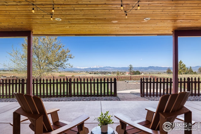 view of patio / terrace with fence and a mountain view