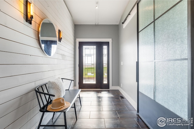 doorway with dark tile patterned floors and wood walls