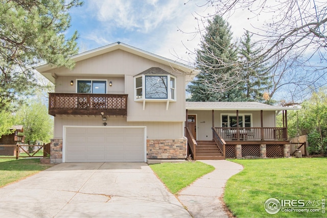 split level home with fence, a front yard, stone siding, an attached garage, and driveway