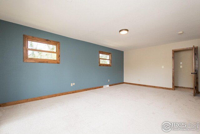 unfurnished room featuring baseboards, visible vents, and light carpet