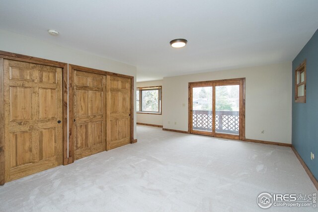 unfurnished bedroom featuring baseboards, access to outside, and light colored carpet