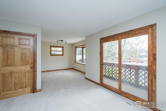 spare room featuring baseboards, visible vents, and light carpet