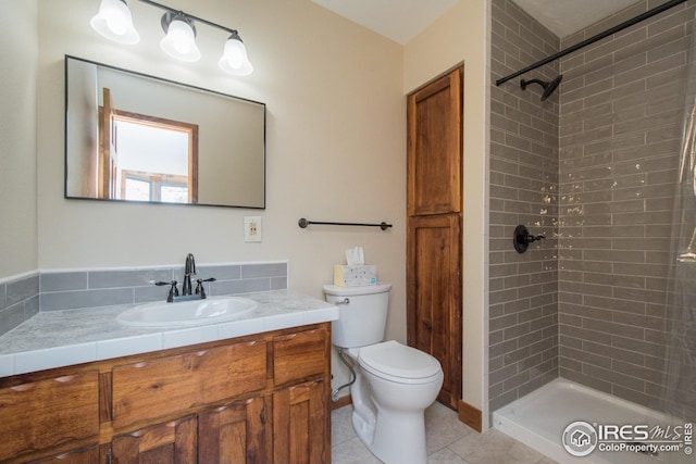 full bathroom featuring vanity, tile patterned flooring, a tile shower, and toilet