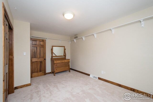 unfurnished bedroom featuring light colored carpet, baseboards, and visible vents