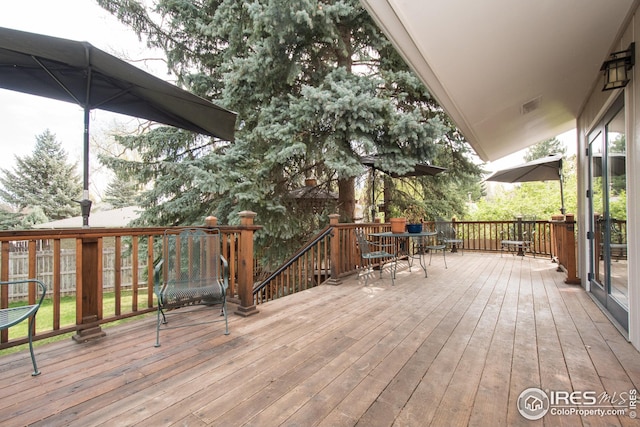 wooden deck with outdoor dining area and visible vents
