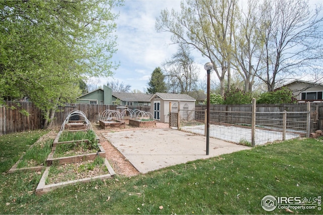 view of yard with a fenced backyard, an outbuilding, a patio area, and a vegetable garden