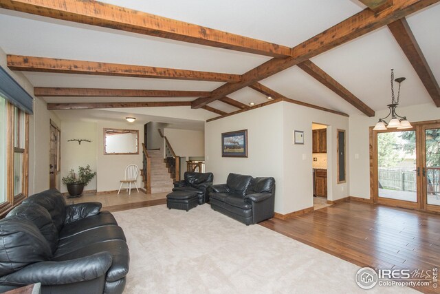 living area with stairs, baseboards, lofted ceiling with beams, and wood finished floors