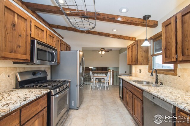 kitchen featuring brown cabinets, ceiling fan, appliances with stainless steel finishes, beam ceiling, and a sink