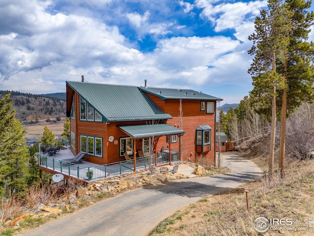 chalet / cabin featuring driveway, a porch, and metal roof