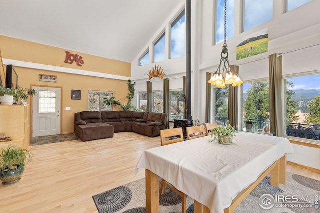 dining area featuring baseboards, a towering ceiling, wood finished floors, and a notable chandelier