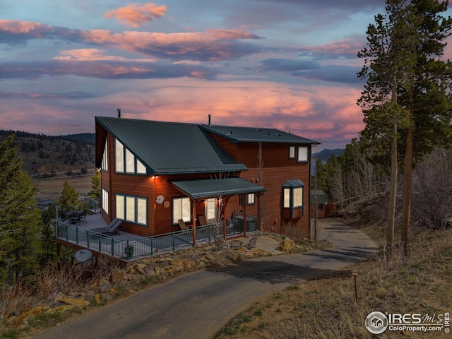 chalet / cabin with a porch, metal roof, and aphalt driveway