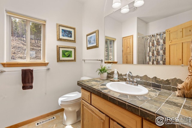 bathroom featuring tile patterned flooring, vanity, toilet, baseboards, and visible vents