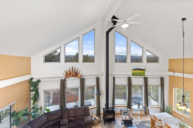 living room with plenty of natural light, a wood stove, a ceiling fan, and wood finished floors