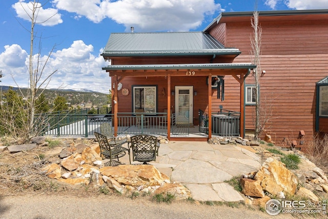 rear view of property featuring central air condition unit, a patio, fence, and metal roof