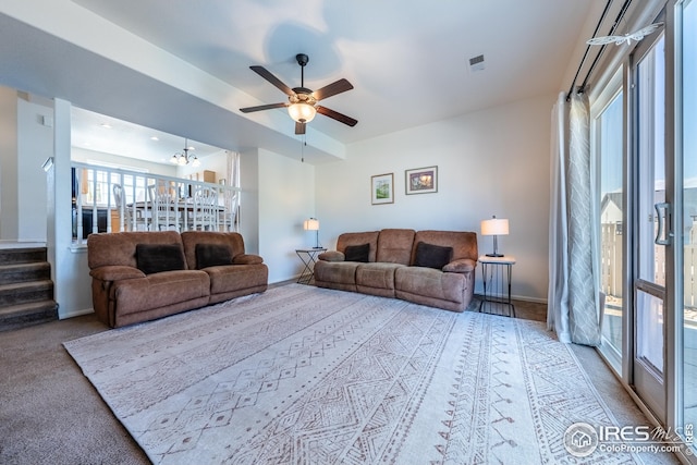 carpeted living area with baseboards, stairs, and ceiling fan
