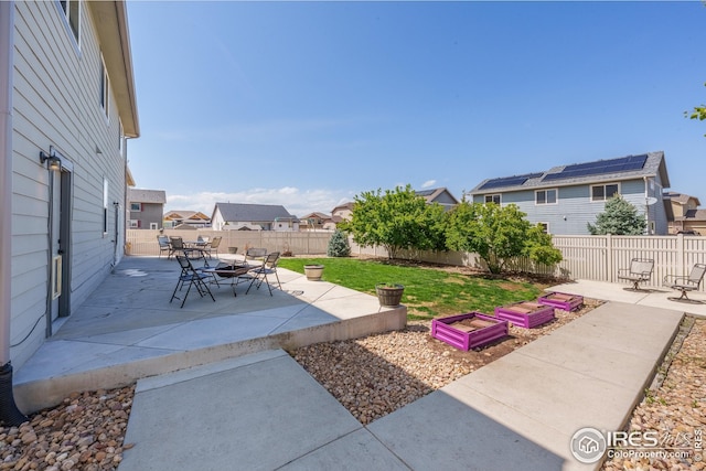 view of yard featuring a residential view, a fenced backyard, a patio area, and a garden