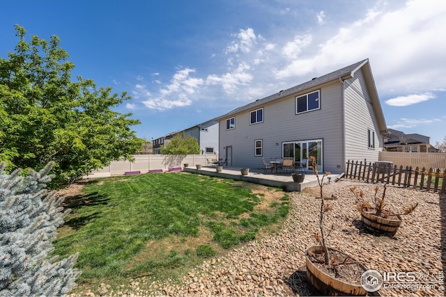 rear view of property featuring a yard and a fenced backyard
