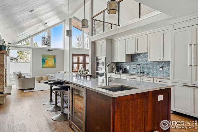 kitchen with backsplash, hardwood / wood-style flooring, a sink, light stone counters, and wine cooler