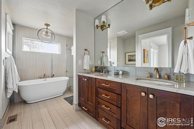 bathroom featuring double vanity, visible vents, a shower stall, and a sink