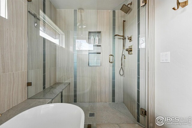 bathroom with a freestanding bath, a healthy amount of sunlight, and a shower stall