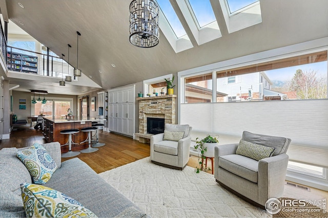 living room featuring a healthy amount of sunlight, high vaulted ceiling, wood finished floors, and visible vents