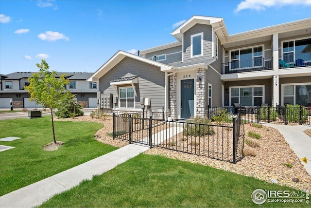 view of property featuring fence private yard, a front lawn, and stone siding