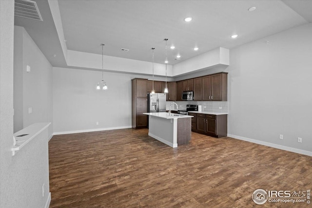 kitchen with visible vents, open floor plan, a kitchen island with sink, and stainless steel appliances