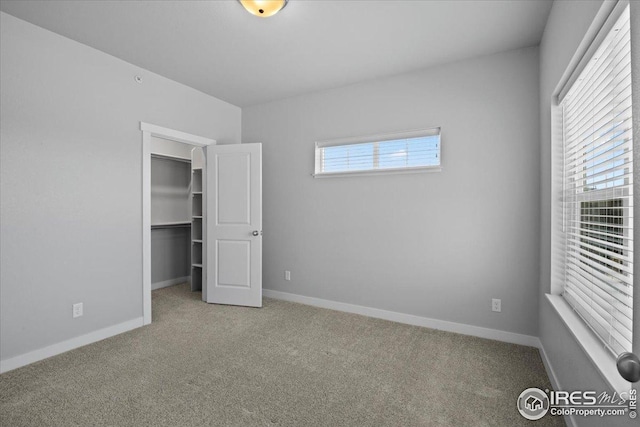 unfurnished bedroom with baseboards, a walk in closet, and carpet