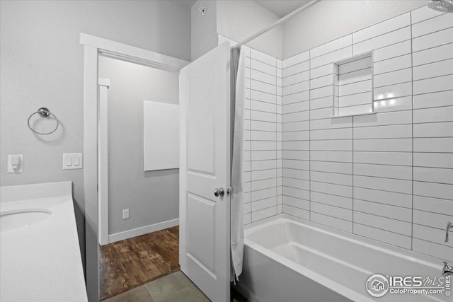 bathroom with baseboards, vanity,  shower combination, and wood finished floors