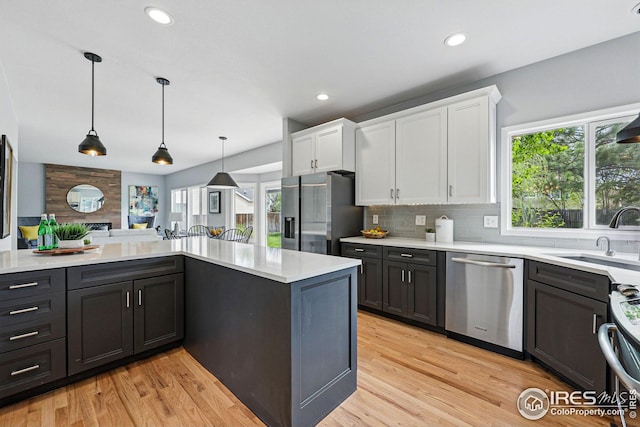 kitchen featuring light countertops, white cabinetry, a sink, a wealth of natural light, and stainless steel appliances