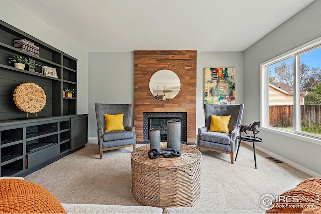 living area featuring baseboards, visible vents, a healthy amount of sunlight, and carpet