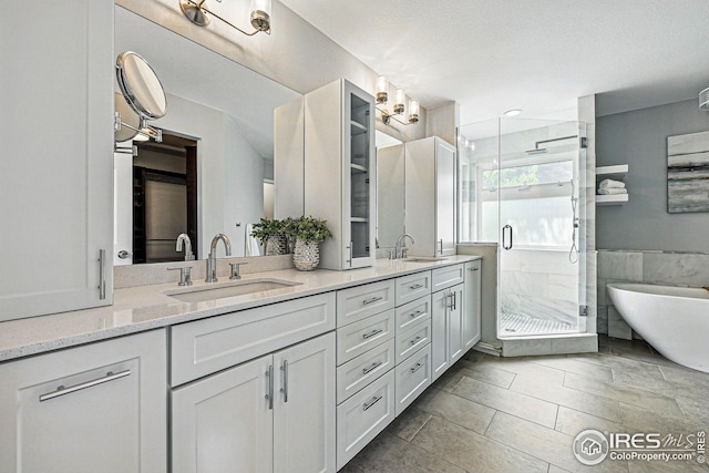 bathroom featuring double vanity, a freestanding tub, a sink, and a stall shower